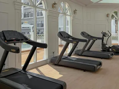 a row of treadmills in a gym with windows at 1BR Lagoon View Luxury Spa Retreat near Miracle Garden in Dubai