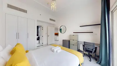 a bedroom with a white bed and a desk at Al Ghaf - Upgraded One Bed with Pool View in Arjan in Dubai