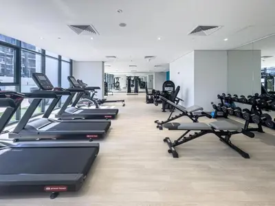 a gym with a row of treadmills and machines at Azizi Riviera - Chic Studio with Balcony in Meydan in Dubai