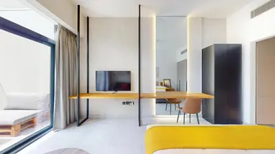 a room with a yellow bench and a table at Oxford Boulevard - Vibrant Studio in JVC in Dubai