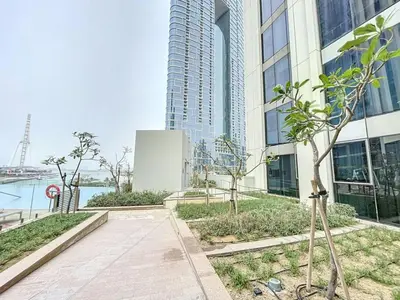 a walkway in front of a tall building with trees at 5242 Tower 2 - One Bed, Low Floor with Canal View in Dubai