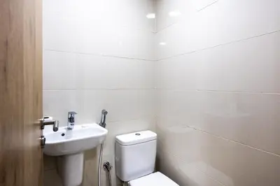 a white bathroom with a toilet and a sink at Dubai Marina Waterfront Stay with Maid Room in Dubai