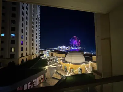 a view of a city at night with a ferris wheel at Stylish 1BR JBR Beachfront in Dubai