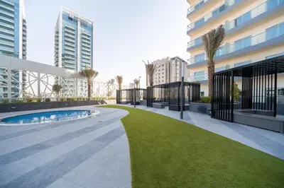 a building with a lawn next to a building at Bella Casa - Luxury 1BR Apartment - Brand New Furniture in Dubai