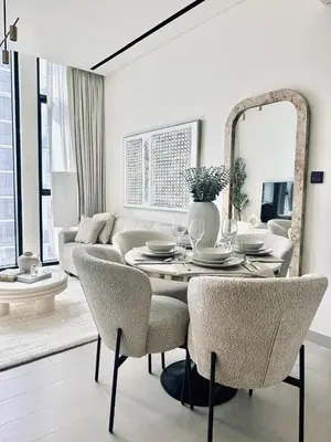 a living room with a table with chairs and a mirror at Cream Toned 1BR Suite with Parking Pool & Gym in Dubai