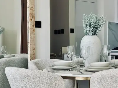 a dining table with plates and glasses and a vase at Cream Toned 1BR Suite with Parking Pool & Gym in Dubai