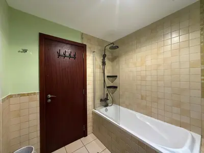 a bathroom with a tub and a toilet and a door at Simbad Friendly Coliving in Dubai