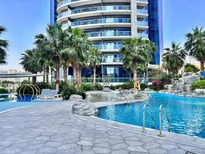 a swimming pool with palm trees and a tall building at FIRST CLASS 2BR Mesmerizing Burj Khalifa View in Dubai