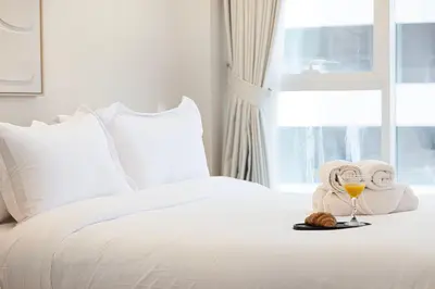 a white bed with a glass of wine and towels at Elegant 3BR Lux Stay in the Heart of Dubai Marina in Dubai