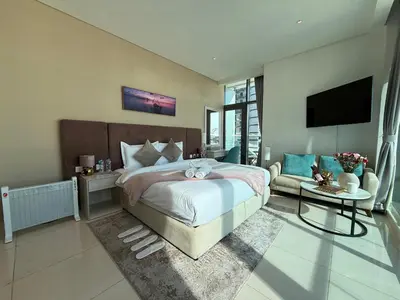 a bedroom with a bed and a tv and a couch at Beachfront Bliss, Seven Palm Studio Apartment in Dubai