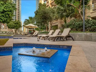 a group of chairs and a fountain in a pool at Versatile 1BR with Burj Khalifa View in Dubai