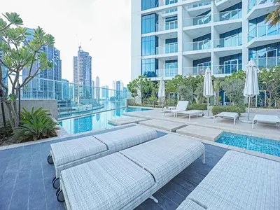 a swimming pool with benches and umbrellas next to a building at Luxury Studio | Near Dubai Mall | Lake View in Dubai