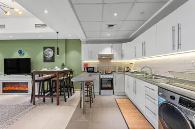 a large kitchen with white cabinets and a fireplace at Modern Apt just Steps to Metro & Lake with Pool andParking in Dubai