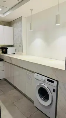 a kitchen with a washing machine under a counter at Oval Tower Retreat, Business Bay in Dubai