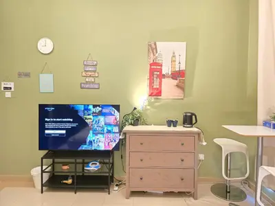 a room with a tv and a dresser and a telephone booth at Charming Studio Near World Trade Center & Subway in Dubai