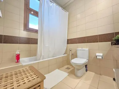 a bathroom with a toilet and a tub and a window at Charming Studio Near World Trade Center & Subway in Dubai