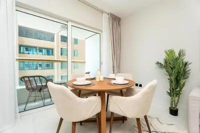 a dining room with a table and chairs and a large window at Gala Guests - Elite Sea View Suites Dubai Marina in Dubai