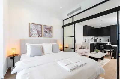 a bedroom with a large white bed and a living room at Gala Guests - Elite Sea View Suites Dubai Marina in Dubai