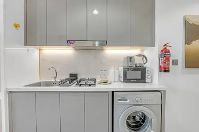 a kitchen with a sink and a washing machine at Waves - Stylish and Comfy Couples Retreat Apt with Balcony in Dubai