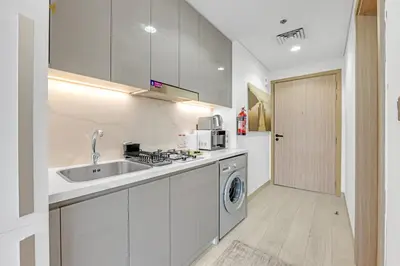 a kitchen with a sink and a washing machine at Waves - Stylish and Comfy Couples Retreat Apt with Balcony in Dubai