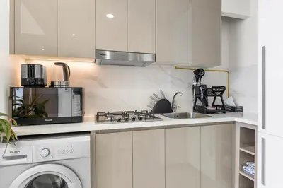 a kitchen with a stove top oven next to a washing machine at Urban Chic Apartments in Dubai