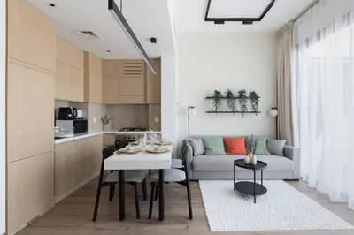 a kitchen and living room with a table and a couch at Modern 1-BR Apartment with Cozy Vibes Pool Gym in Dubai