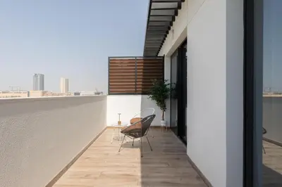 a balcony with a table and chairs on a building at Modern 1-BR Apartment with Cozy Vibes Pool Gym in Dubai