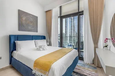a bedroom with a blue bed and a large window at Stylish Apartment in Meydan in Dubai