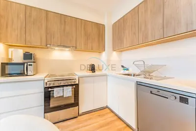 a kitchen with white cabinets and a stove top oven at Next to Dubai Hills Park 1BR, Moments from Dubai Hills Mall, Executive Residences 2, Dubai Hills Estate by Deluxe Holiday Homes in Dubai