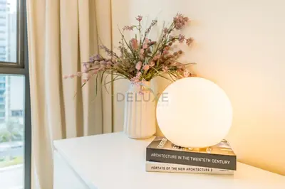 a table with a vase and a mirror and books at Next to Dubai Hills Park 1BR, Moments from Dubai Hills Mall, Executive Residences 2, Dubai Hills Estate by Deluxe Holiday Homes in Dubai