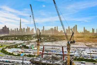 a construction site with cranes in front of a city at Spacious 3BR Family Stay with Balcony Views of Burj and City Lights in Dubai