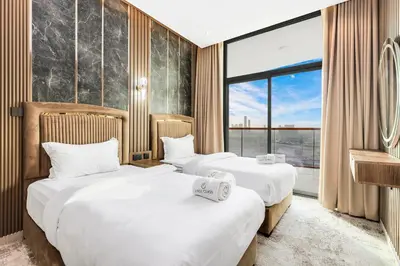 two beds in a hotel room with a large window at Spacious 3BR Family Stay with Balcony Views of Burj and City Lights in Dubai