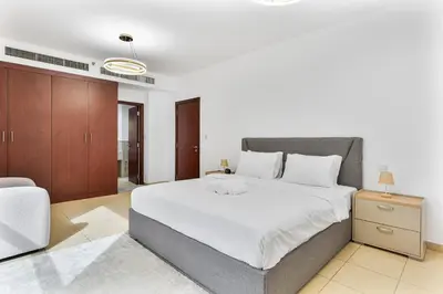 a bedroom with a large bed and a couch at Chic 2-bed Oasis with Marina Views Walk to Beach! in Dubai