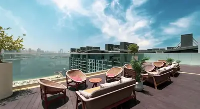 a patio with chairs and tables and a view of the water at Beachfront Bliss Seven Palm in Dubai