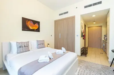 a bedroom with a large white bed with towels on it at PVH - Azizi Riviera - Lovely Studio near Downtown in Dubai