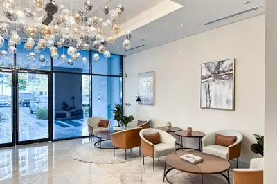 a lobby with chairs and tables and a chandelier at PVH - Azizi Riviera - Lovely Studio near Downtown in Dubai
