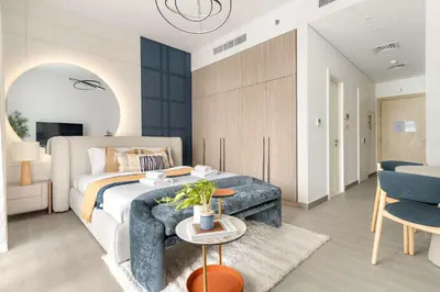 a bedroom with a bed and a couch and a table at Silkhaus Chic Studio in Sobha Hartland at Kensington in Dubai