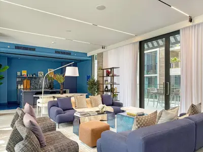 a living room with purple furniture and a blue wall at Silkhaus Chic Studio in Sobha Hartland at Kensington in Dubai