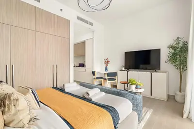 a bedroom with a bed and a flat screen tv at Silkhaus Chic Studio in Sobha Hartland at Kensington in Dubai