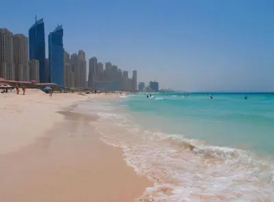 a beach with people in the water and buildings at Luxury Modern Apt in JBR 2 MIN to BEACH in Dubai
