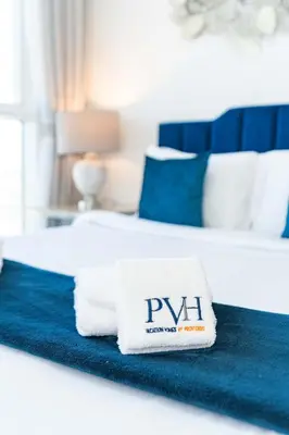 a white towel with the word pyu sits on a bed at PVH - Golf Vita - 1BR with Golf Course View in Dubai