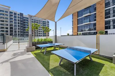 three ping pong tables on a rooftop with buildings at Sleek Cozy Apartments in Meydan in Dubai