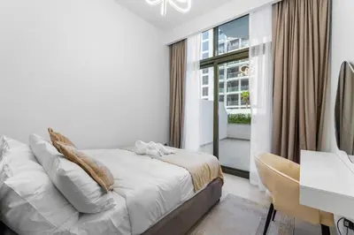 a bedroom with a bed and a desk and a window at Sleek Cozy Apartments in Meydan in Dubai