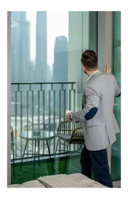 a man in a suit looking out of a window at Serene 2BR Burj View DT Dubai in Dubai