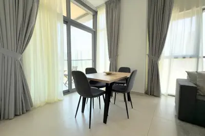 a dining table and chairs in a room with windows at 1 Bedroom Apt with Stunning Burj Khalifa View in Dubai