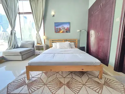 a bedroom with a large bed and a chair at Chic studio in Central Dubai in Dubai