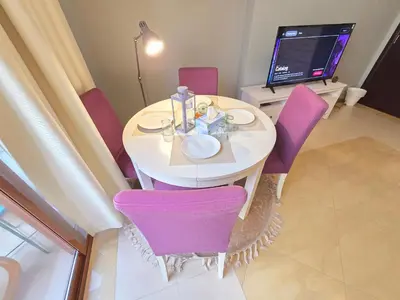 a white table with purple chairs and a television at Airy and Bright Near DIFC and the Subway in Dubai
