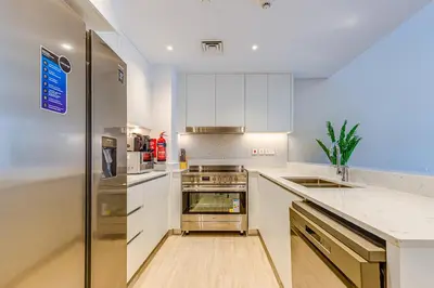 a kitchen with white cabinets and a stainless steel refrigerator at Elegant 2 Bedroom Apartment - Jadeel 2, Madinat Jumeirah - Allsopp & Allsopp in Dubai