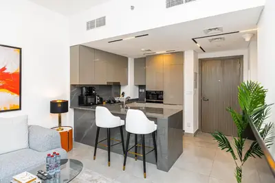 a kitchen and living room with white stools at Escape24 Brand New 1BR with City View near Burj Khalifa in Dubai