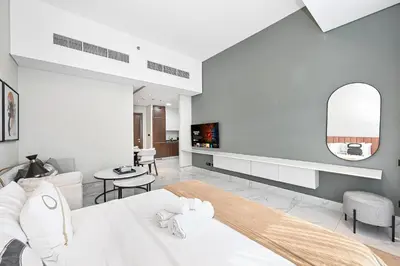 a bedroom with a bed and a living room at Unwind in a Stylish Studio with Pool, Sauna, and Stunning City Views in Dubai